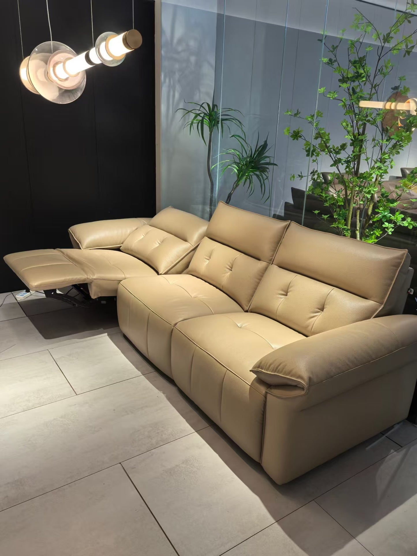 Beige sectional sofa in a modern living room with plants and a light fixture.