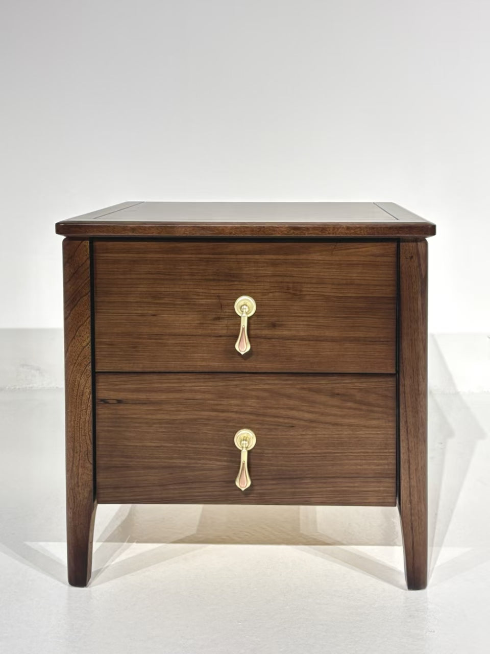 Classic walnut wood nightstand with two brass-handled drawers and tapered legs – perfect for elegant bedrooms.