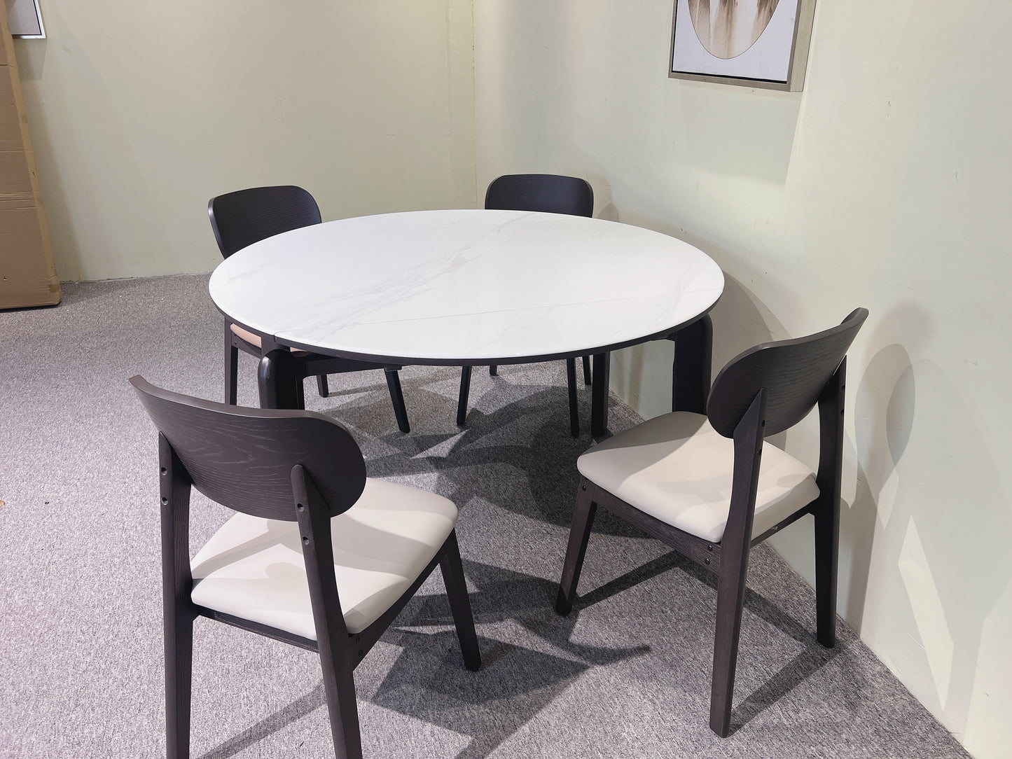 Round white table with four dark chairs in a room.