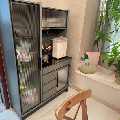 Cabinet with glass doors in a room with a plant and a chair.